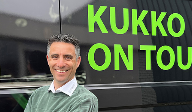 Ein Kukko Mitarbeiter vor einem schwarzen Van mit der Aufschrift "KUKKO on Tour"